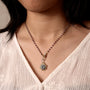 Necklace with a pendant worn by a person in a white top.-2