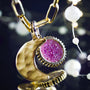 Gold necklace with a pink gemstone pendant against a blurred background-3