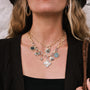 Close-up of a person wearing a Waxing Poetic Soul Friend Pendant with various charms against a neutral background.-4